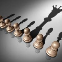 leadership - fundsforNGOs Row of brown chess pawns casting a large shadow of a reaching hand, suggesting control or manipulation.
