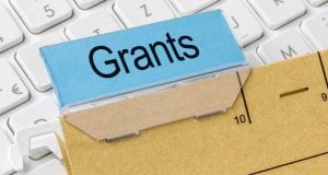 Blue card labeled 'Grants' resting on a ruler over a white keyboard, symbolizing grant funding and measurement