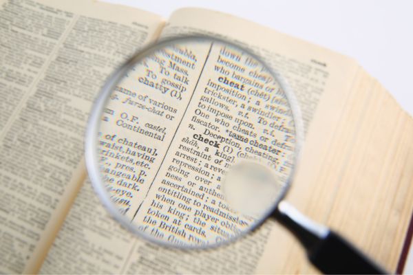 research 3 - fundsforNGOs Close-up of a magnifying glass held over an open dictionary, magnifying a few words on the page.