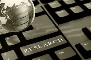 Keyboard with a prominent 'RESEARCH' key and a globe beside it, symbolizing online or global research.