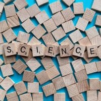 science 2 - fundsforNGOs Wooden letter blocks arranged to spell 'SCIENCE' on a bright blue background, with scattered blocks around.
