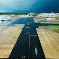 transport - fundsforNGOs Runway at an airport with taxis and planes parked at gates under a cloudy blue sky; perspective from a window or elevated view.