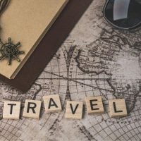 travel - fundsforNGOs Scrabble tiles spell 'TRAVEL' on a vintage map with a notebook, sunglasses, and a compass pendant.