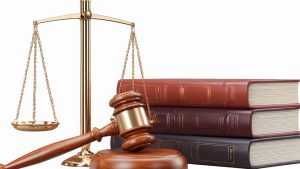 Gold scales of justice beside a wooden gavel and a stack of legal books, symbolizing law and justice.